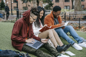 Cheerful diverse classmates studying in park