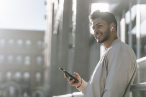 Happy man communicating via smartphone on street