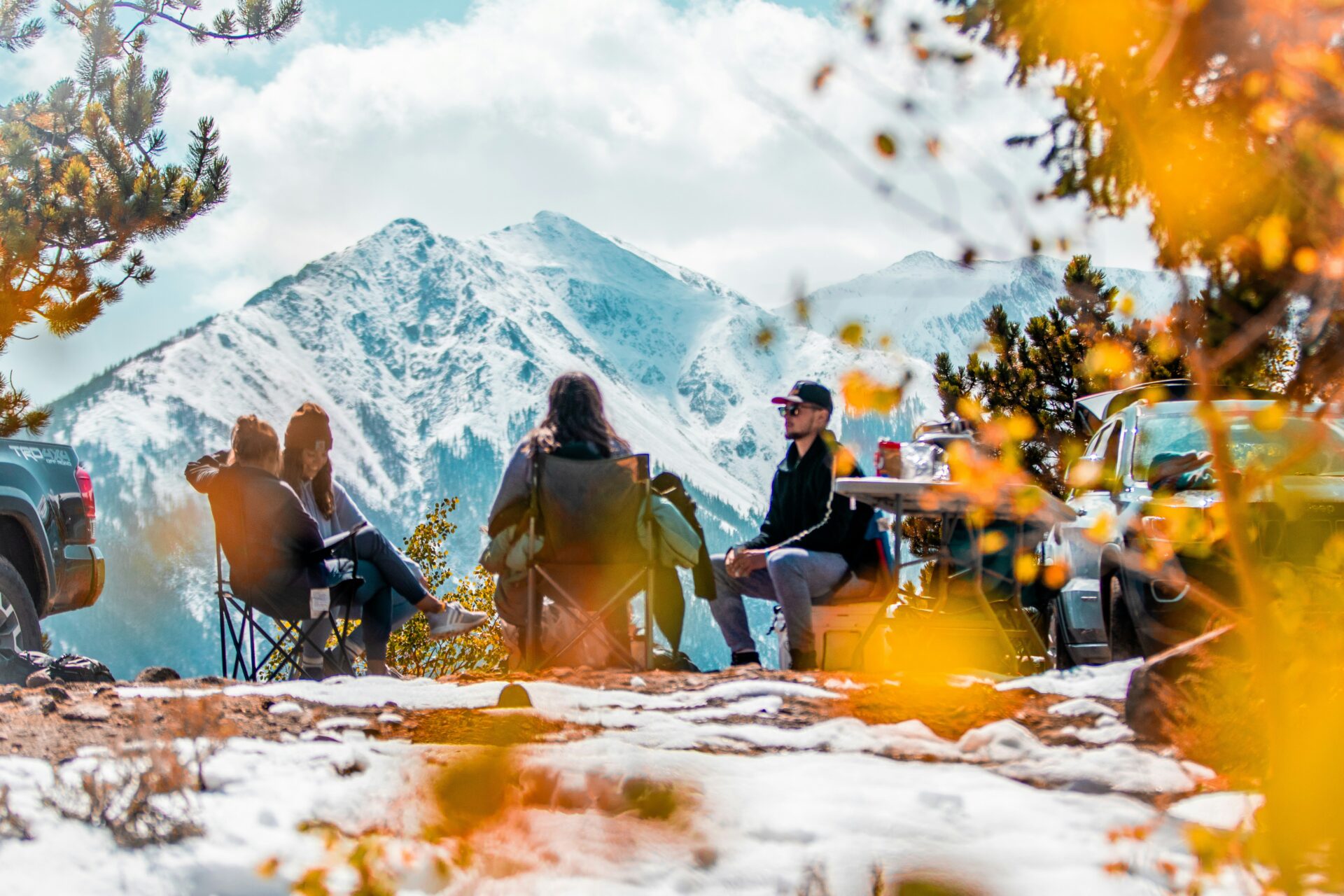 friends sitting around campsite with epic mountain view in Colorado fall